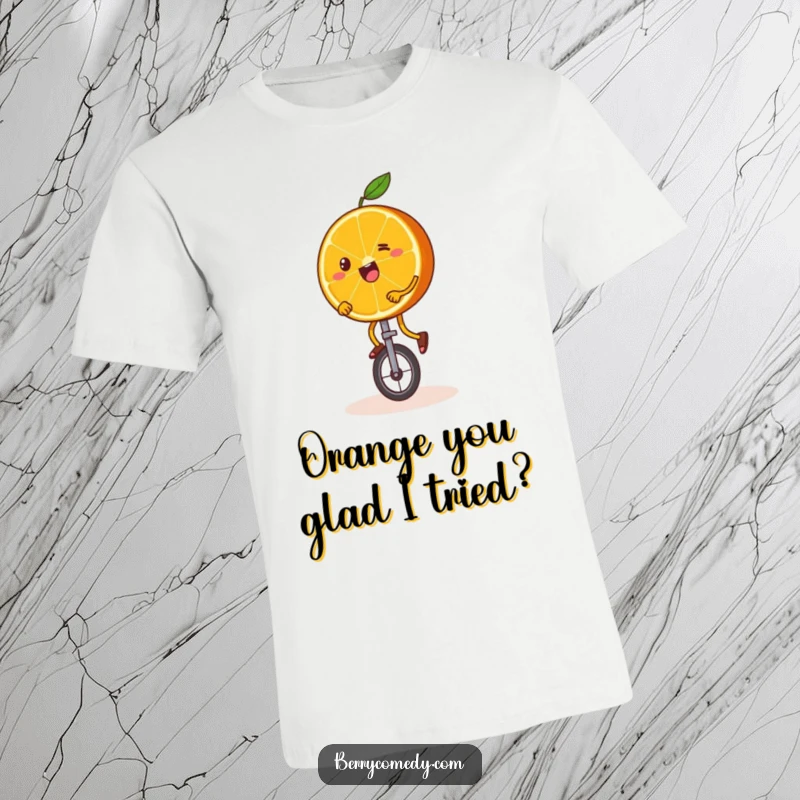 Funny T-shirt featuring a happy orange slice with wobbly legs, humorously attempting to ride a miniature unicycle with a determined expression.